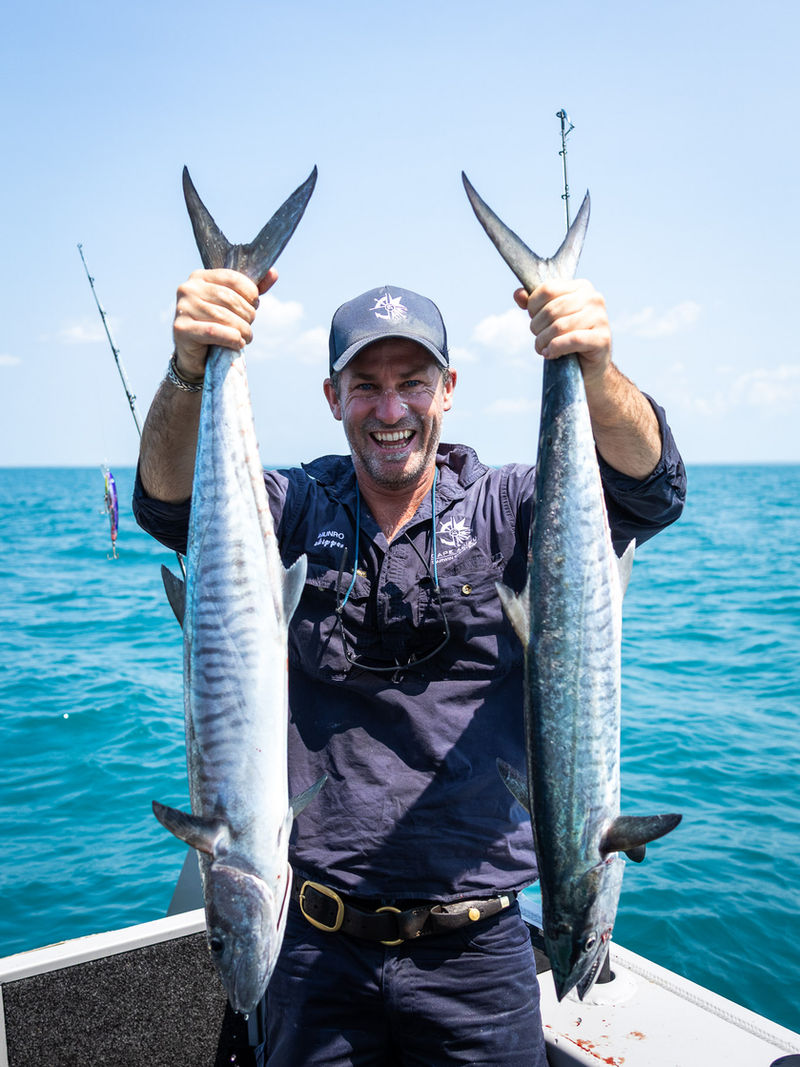 Skipper holding two Spanish mackerel on a Cape Adieu offshore fishing charter, Darwin